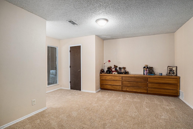 carpeted empty room with a textured ceiling, visible vents, and baseboards