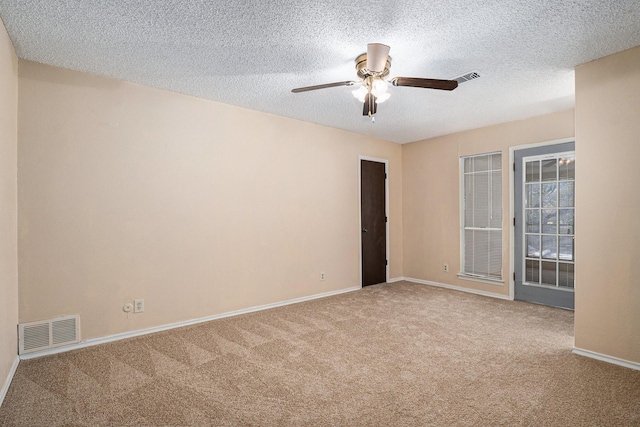 empty room featuring baseboards, visible vents, a textured ceiling, and carpet flooring