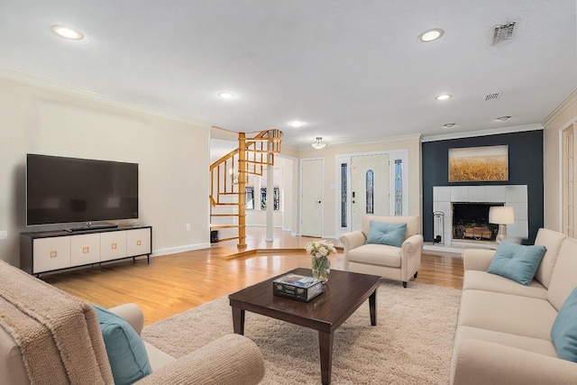 living area featuring stairs, wood finished floors, visible vents, and crown molding