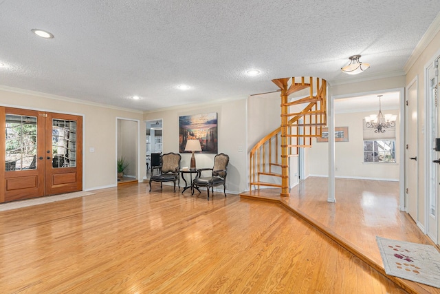 entryway with french doors, crown molding, stairway, light wood-style floors, and a textured ceiling