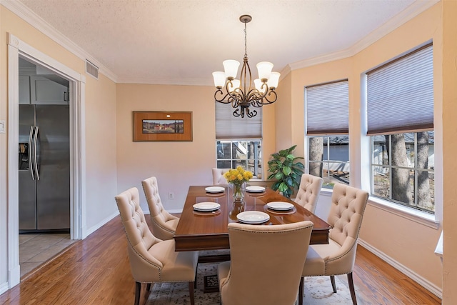 dining area featuring wood finished floors, visible vents, and crown molding