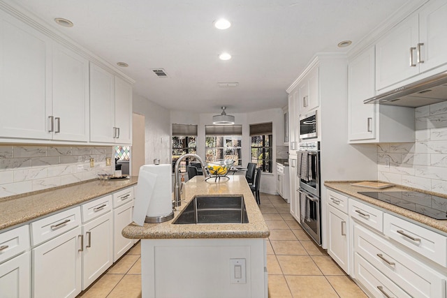 kitchen with under cabinet range hood, a sink, visible vents, white cabinetry, and tasteful backsplash