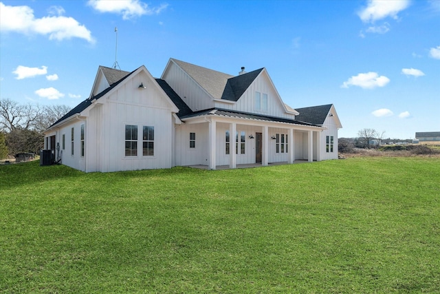 rear view of property with cooling unit, a standing seam roof, a lawn, board and batten siding, and metal roof