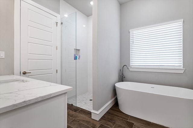 full bath featuring wood finish floors, a freestanding tub, baseboards, and walk in shower