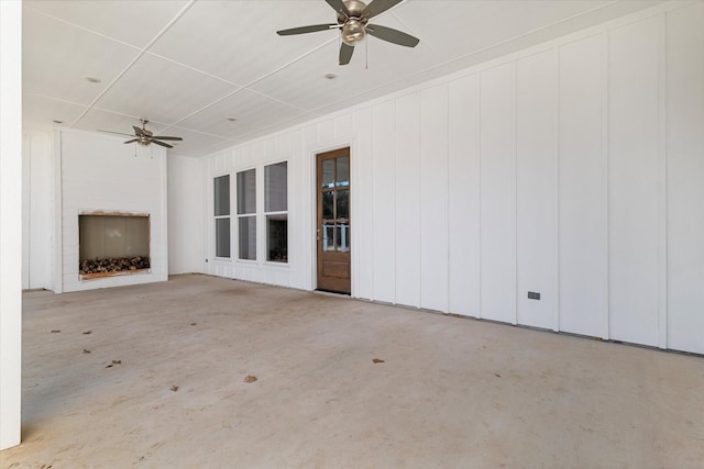 unfurnished living room with concrete flooring, an outdoor fireplace, and a ceiling fan