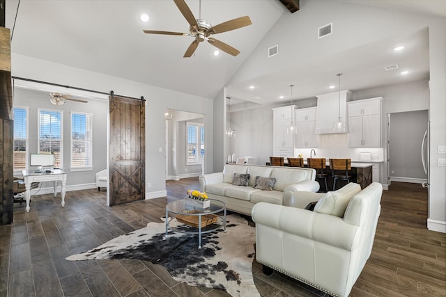 living room featuring dark wood-style floors, visible vents, ceiling fan, and a barn door