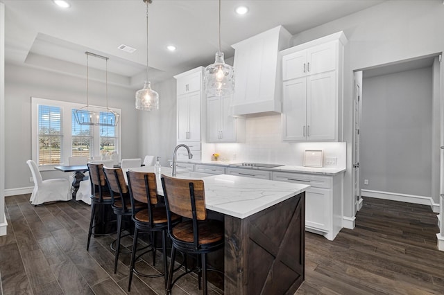 kitchen featuring tasteful backsplash, visible vents, premium range hood, a raised ceiling, and dark wood-style flooring