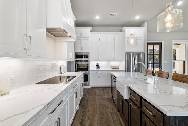 kitchen featuring visible vents, backsplash, wall chimney range hood, stainless steel appliances, and a sink