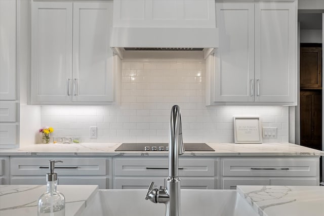 kitchen featuring tasteful backsplash, wall chimney exhaust hood, and white cabinetry