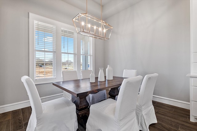 dining space featuring baseboards, an inviting chandelier, and wood finished floors