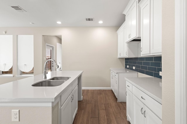 kitchen with tasteful backsplash, visible vents, a sink, and dark wood-style floors