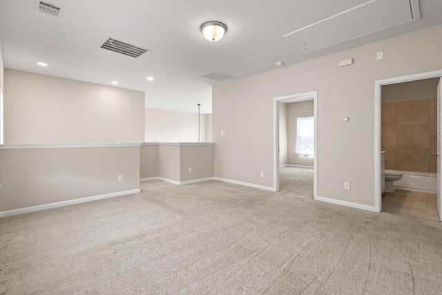 unfurnished room featuring attic access, visible vents, baseboards, and light colored carpet