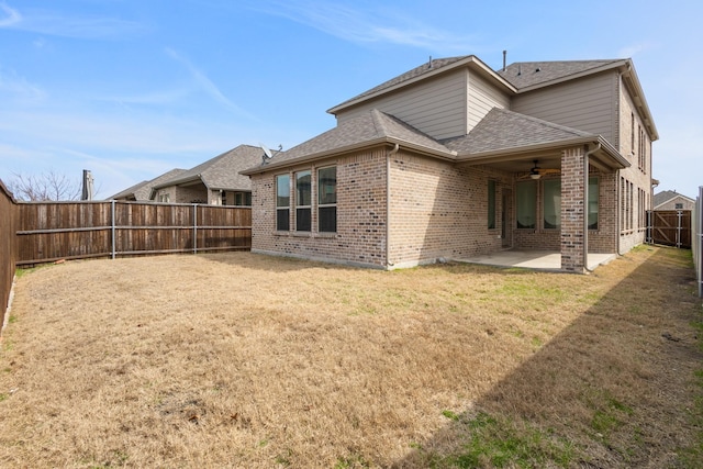 rear view of house with a lawn, a ceiling fan, a fenced backyard, a patio area, and brick siding