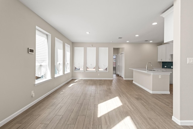 unfurnished living room featuring light wood-type flooring, baseboards, and recessed lighting