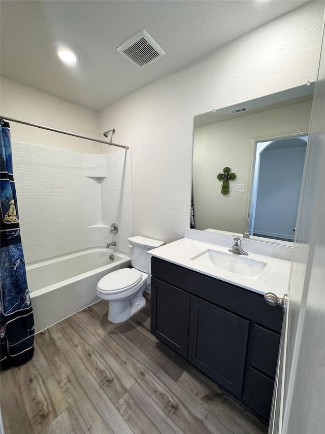 full bath featuring visible vents, shower / bathtub combination with curtain, toilet, vanity, and wood finished floors