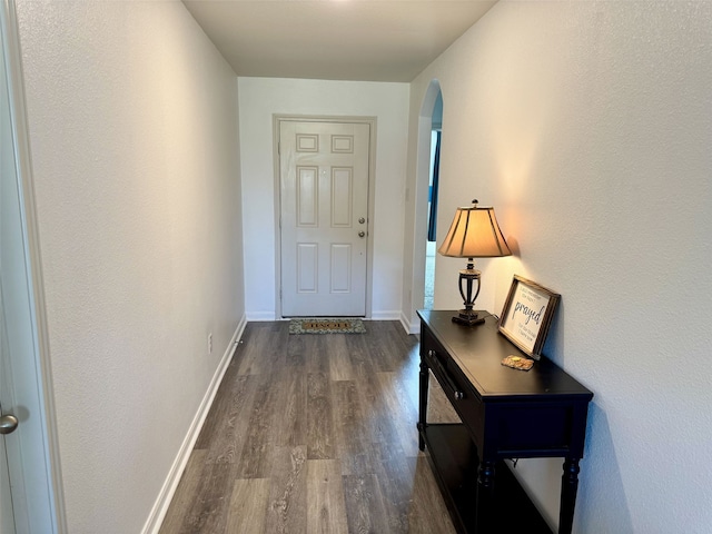 entryway featuring dark wood-style floors, arched walkways, and baseboards