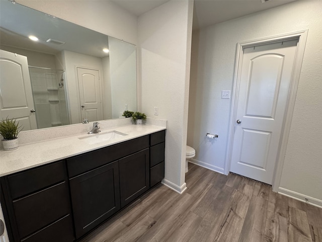 bathroom featuring toilet, wood finished floors, vanity, baseboards, and a shower stall