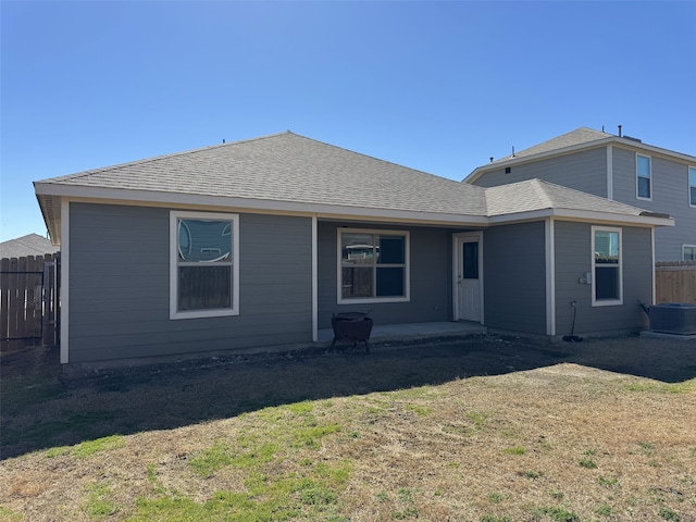 back of property with a shingled roof, a lawn, a patio area, and fence