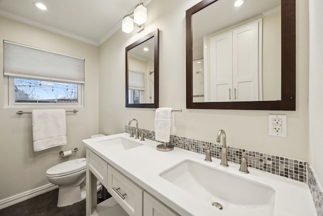 full bath featuring toilet, crown molding, double vanity, and a sink