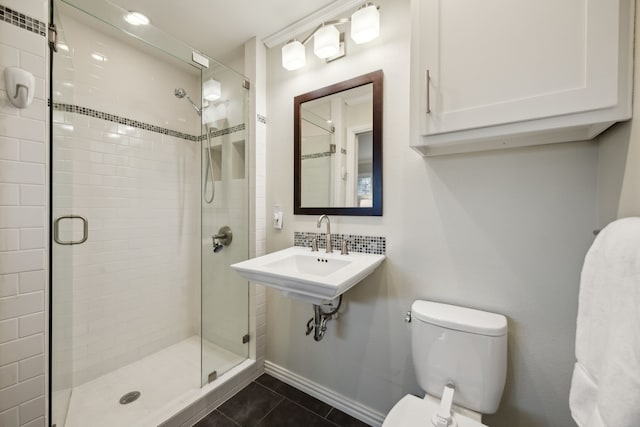 full bathroom featuring toilet, a stall shower, a sink, baseboards, and tile patterned floors