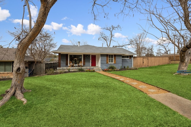 view of front of property featuring a trampoline, a shingled roof, covered porch, fence, and a front lawn