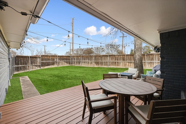 wooden deck with outdoor dining area, a lawn, and a fenced backyard