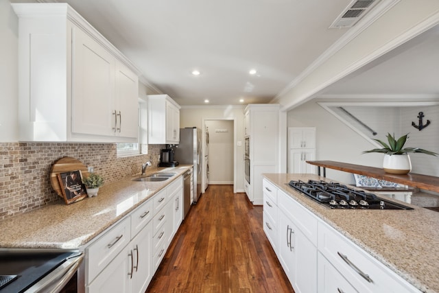 kitchen with visible vents, white cabinets, stainless steel appliances, crown molding, and a sink