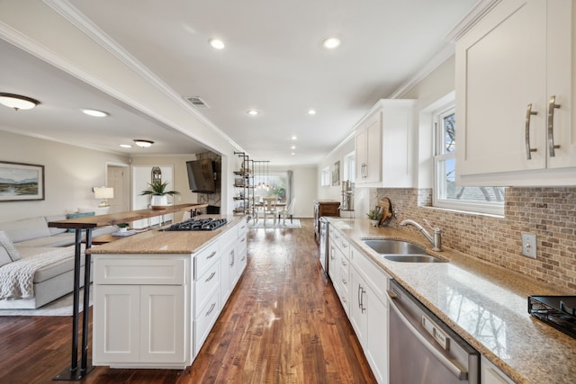 kitchen featuring dishwasher, ornamental molding, open floor plan, a kitchen bar, and a sink