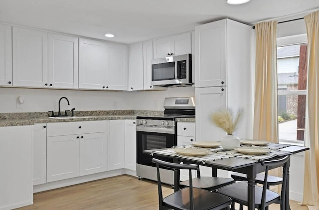 kitchen with white cabinets, plenty of natural light, stainless steel appliances, and a sink