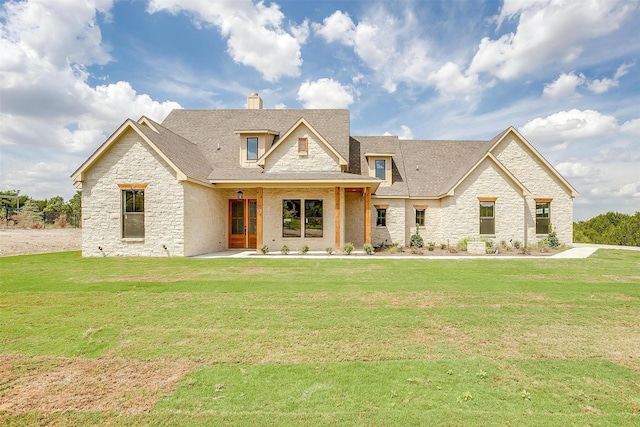 view of front of house with stone siding, a shingled roof, a chimney, and a front yard