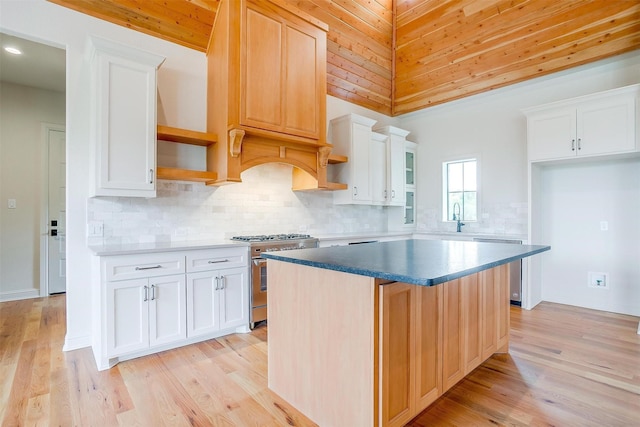 kitchen featuring stainless steel appliances, light wood finished floors, open shelves, and white cabinetry