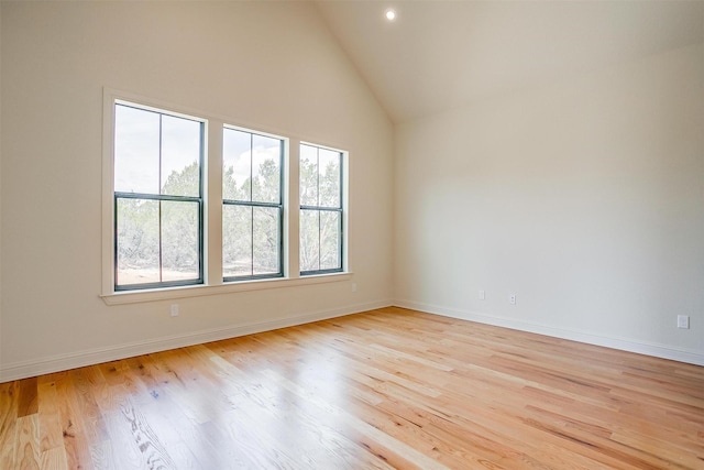 spare room featuring high vaulted ceiling, recessed lighting, light wood-style flooring, and baseboards