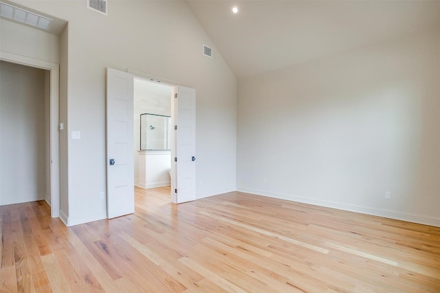 unfurnished bedroom with high vaulted ceiling, visible vents, and light wood-style floors