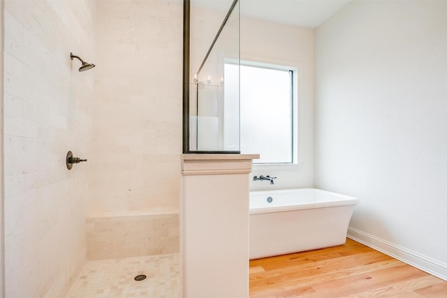 full bath with a soaking tub, a tile shower, baseboards, and wood finished floors