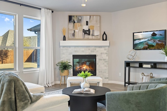 living room with a brick fireplace, wood finished floors, and baseboards