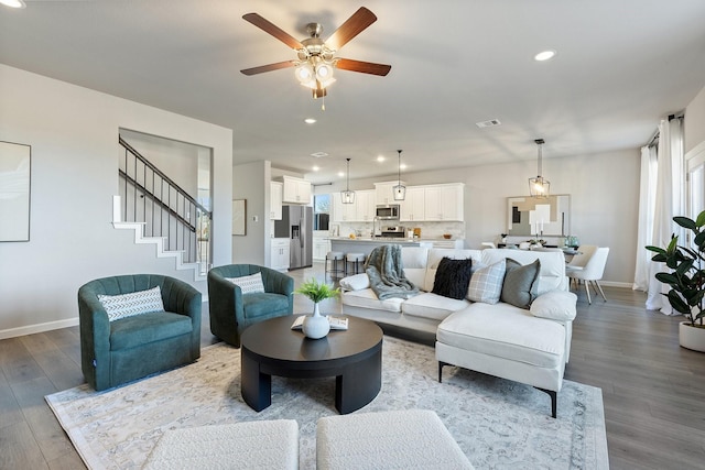 living room featuring stairs, recessed lighting, baseboards, and wood finished floors