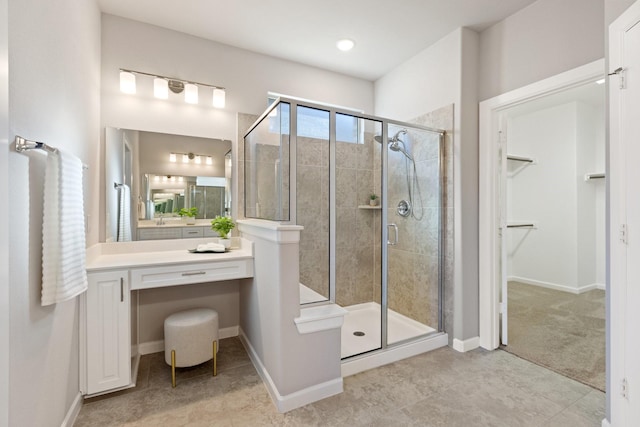 full bath featuring a stall shower, a spacious closet, baseboards, and vanity