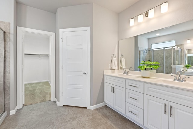 full bathroom featuring double vanity, a stall shower, a spacious closet, and a sink