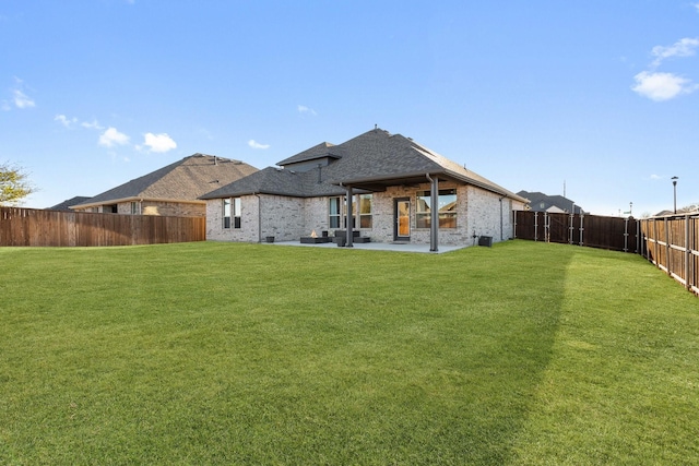 back of property featuring a patio, a fenced backyard, brick siding, a shingled roof, and a yard