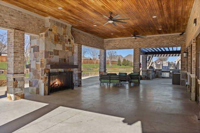 view of patio featuring a ceiling fan, an outdoor stone fireplace, and area for grilling