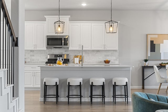 kitchen featuring appliances with stainless steel finishes, light countertops, a kitchen island with sink, and a breakfast bar area