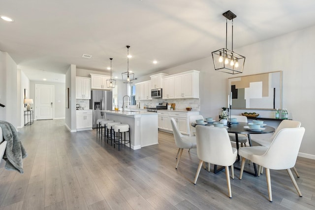 dining space with recessed lighting, light wood-style flooring, and baseboards