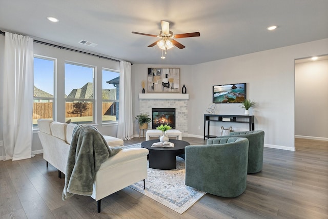 living area featuring visible vents, wood finished floors, and a glass covered fireplace