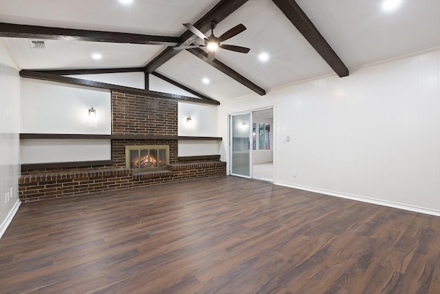 unfurnished living room with lofted ceiling with beams, ceiling fan, wood finished floors, visible vents, and a brick fireplace