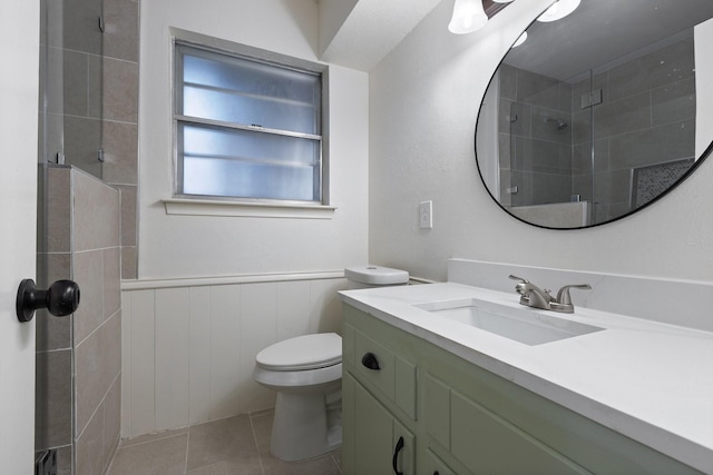 full bath with tile patterned flooring, toilet, vanity, wainscoting, and a stall shower