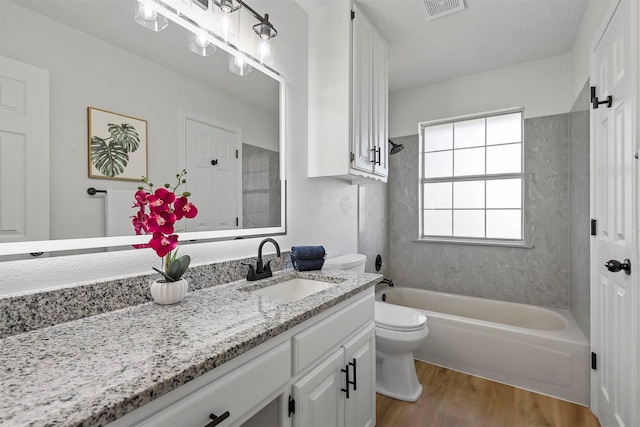 bathroom featuring visible vents, toilet, washtub / shower combination, vanity, and wood finished floors