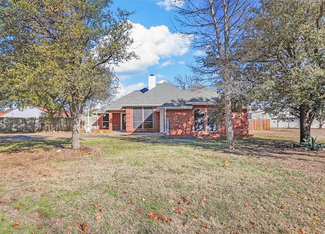 exterior space with brick siding, a chimney, a front yard, a sunroom, and fence