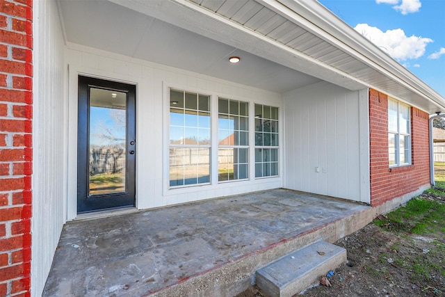 doorway to property featuring brick siding and a patio