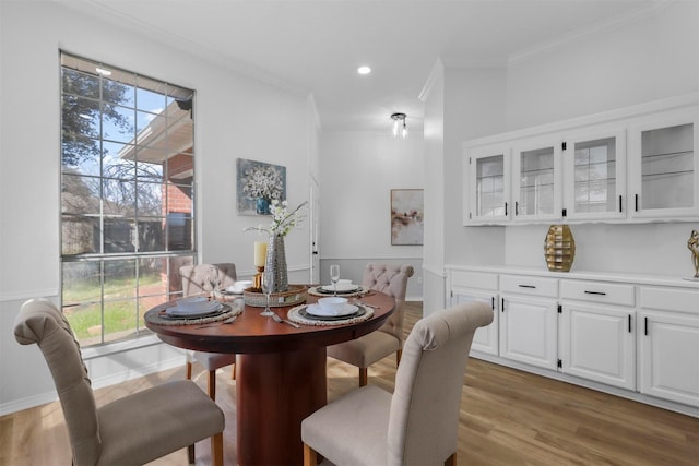 dining room with light wood finished floors, baseboards, crown molding, and recessed lighting