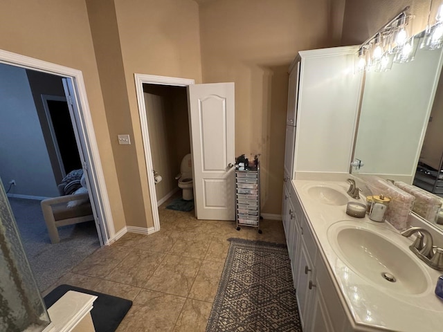 full bathroom with a high ceiling, baseboards, a sink, and tile patterned floors